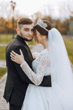 Genç bir gelin ve damat sonbahar güneşinin ışınlarında şefkatle kucaklaşır. Şefkatli ve güzel genç kız gelin. Bir adam sevgilisini öper. Güzel bir bahçenin arka planında