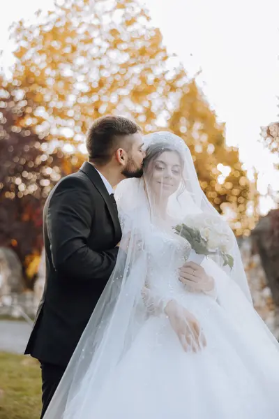 Sonbahar parkında yürüyüş yapan düğün çifti. Güzel beyaz elbiseli gelin. Aşk ve ilişki kavramı. Doğada damat ve gelin