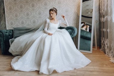 İnanılmaz güzel bir gelin yatak odasında bir yatakta oturur. Gelin sabahı. Parlak bir odadaki bir yatakta oturan güzel elbiseli muhteşem bir gelin. .