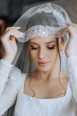 Beyaz gelinlik içinde duvak tutan genç bir gelin otel odasında esmer gelin portresi, düğünden önceki sabah..