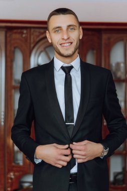 Damat düğünden önceki sabah ceketinin düğmelerini iliklemiş. Takım elbiseli bir adamın yakın çekimi. İş adamı takım elbise giyer. Bir adam ceketinin düğmelerini bağlar..