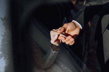 Arabada oturan güzel bir gelin, elini kocasına uzatır. Elinde bir buket çiçekle güzel bir gelin şık ve pahalı bir arabada oturuyor..