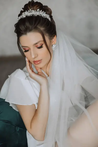 Closeup brunette bride with fashion wedding hairstyle and makeup. A youthful bride with a sophisticated bridal hairdo indoors by a window