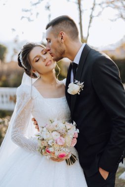 Genç bir gelin ve damat sonbahar güneşinin ışınlarında şefkatle kucaklaşır. Şefkatli ve güzel genç kız gelin. Bir adam sevgilisini öper. Güzel bir bahçenin arka planında