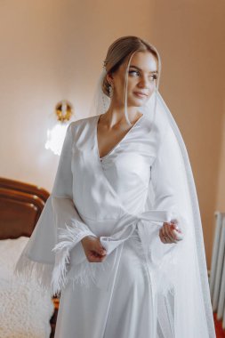 Moda düğün saç stili ve makyajlı sarışın gelin. Pencere kenarında entelektüel bir saç modeli olan genç bir gelin.