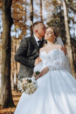 Genç bir gelin ve damat sonbahar güneşinin ışınlarında şefkatle kucaklaşır. Şefkatli ve güzel genç kız gelin. Bir adam sevgilisini öper. Güzel bir bahçenin arka planında