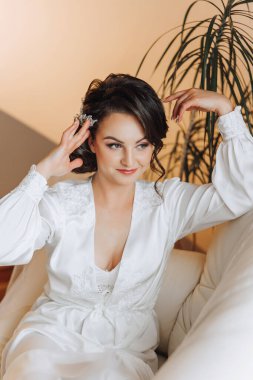 Yatak odasında beyaz bornozlu inanılmaz güzel bir kızın portresi. Gelin düğün töreninden önce sabah poz veriyor..