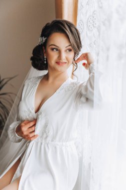 Yatak odasında beyaz bornozlu inanılmaz güzel bir kızın portresi. Gelin düğün töreninden önce sabah poz veriyor..