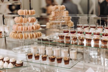 Düğün yemeği için bademli kurabiyeler, tatlı kekler. Lezzetli bir karşılama, lüks bir tören. Tatlı ve tatlılı bir masa. Masada ya da tabakta lezzetli renkli Fransız tatlıları. Şeker çubuğu.