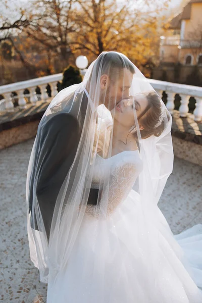 Genç bir gelin ve damat sonbahar güneşinin ışınlarında şefkatle kucaklaşır. Şefkatli ve güzel genç kız gelin. Bir adam sevgilisini öper. Güzel bir bahçenin arka planında