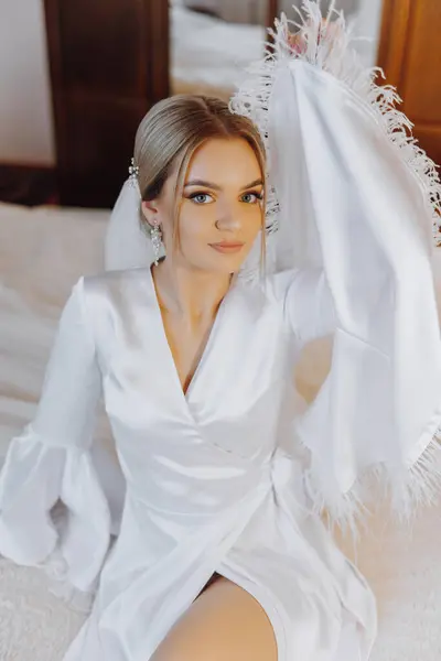 Closeup blond bride with fashion wedding hairstyle and makeup. A youthful bride with a sophisticated bridal hairdo indoors by a window