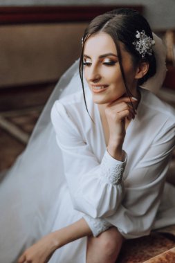 Yatak odasında beyaz bornozlu inanılmaz güzel bir kızın portresi. Gelin düğün töreninden önce sabah poz veriyor..
