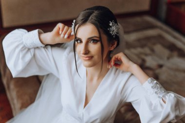 Yatak odasında beyaz bornozlu inanılmaz güzel bir kızın portresi. Gelin düğün töreninden önce sabah poz veriyor..