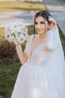 Portre. Elbise ve peçeli esmer bir gelin şık bir taçla buketle poz veriyor. Gümüş mücevherler. Güzel makyaj ve saç. Sonbahar düğünü. kutlama