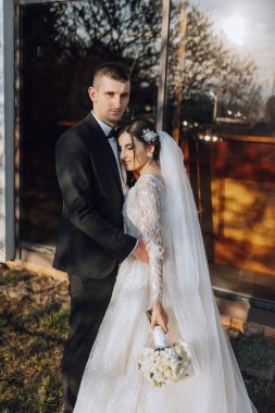 Genç bir gelin ve damat sonbahar güneşinin ışınlarında şefkatle kucaklaşır. Şefkatli ve güzel genç kız gelin. Bir adam sevgilisini öper. Güzel bir bahçenin arka planında