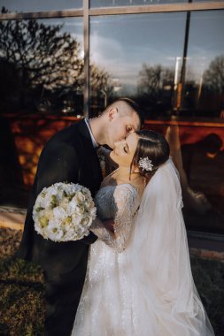 Genç bir gelin ve damat sonbahar güneşinin ışınlarında şefkatle kucaklaşır. Şefkatli ve güzel genç kız gelin. Bir adam sevgilisini öper. Güzel bir bahçenin arka planında