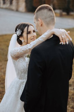 Genç bir gelin ve damat sonbahar güneşinin ışınlarında şefkatle kucaklaşır. Şefkatli ve güzel genç kız gelin. Bir adam sevgilisini öper. Güzel bir bahçenin arka planında