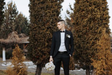 Bir sonbahar gününde zarif bir takım elbiseyle yakışıklı bir damadın portresi. Açık hava fotoğrafı. Takım elbiseli yakışıklı bir adam..