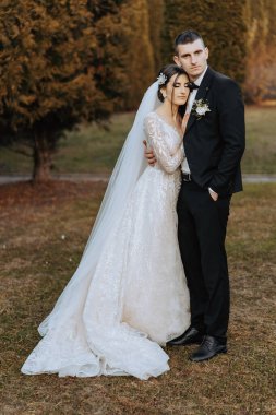 Genç bir gelin ve damat sonbahar güneşinin ışınlarında şefkatle kucaklaşır. Şefkatli ve güzel genç kız gelin. Bir adam sevgilisini öper. Güzel bir bahçenin arka planında