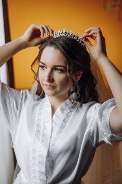 Yatak odasında beyaz bornozlu inanılmaz güzel bir kızın portresi. Gelin düğün töreninden önce sabah poz veriyor..