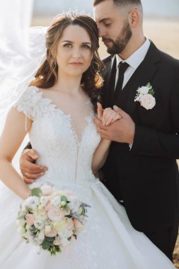 Genç bir gelin ve damat sonbahar güneşinin ışınlarında şefkatle kucaklaşır. Şefkatli ve güzel genç kız gelin. Bir adam sevgilisini öper. Güzel bir bahçenin arka planında