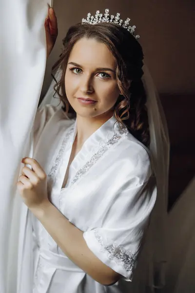 portrait of an incredibly beautiful girl bride in a white robe in the bedroom, the bride poses in the morning before the wedding ceremony.