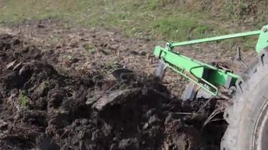 Dağlık bir alanda küçük bir traktör. Bir traktör, küçük bir çiftlikte sabanla tarlayı sürüyor. Güzel 4K video. Pulluk yakın çekim.