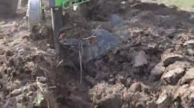 Dağlık bir alanda küçük bir traktör. Bir traktör, küçük bir çiftlikte sabanla tarlayı sürüyor. Güzel 4K video. Pulluk yakın çekim.