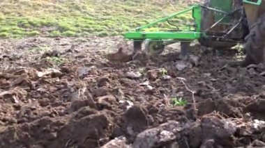 Dağlık bir alanda küçük bir traktör. Bir traktör, küçük bir çiftlikte sabanla tarlayı sürüyor. Güzel 4K video. Pulluk yakın çekim.
