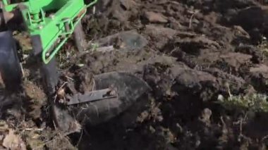 Dağlık bir alanda küçük bir traktör. Bir traktör, küçük bir çiftlikte sabanla tarlayı sürüyor. Güzel 4K video. Pulluk yakın çekim.