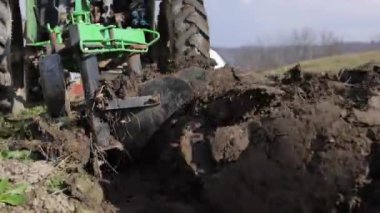 Yetişkin bir adam küçük bir traktör sürer ve tarlayı sürer. Tarım faaliyetleri. Saban toprağı keser ve sebze ekmeye hazırlar. Tarımsal makineler üzerinde çalışan bir adam. 4k