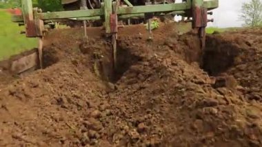 Bir traktör kırsalda toprak yetiştirir. Bir traktör, küçük bir çiftlikte sabanla tarlayı sürüyor. 4K video. Araziyi yakından işlemek için Tiller.