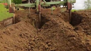 Bir traktör kırsalda toprak yetiştirir. Bir traktör, küçük bir çiftlikte sabanla tarlayı sürüyor. 4K video. Araziyi yakından işlemek için Tiller.