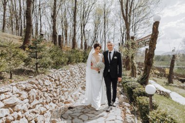 Gelin ve damat düğün günlerinde el ele tutuşarak doğada yürüyorlar.