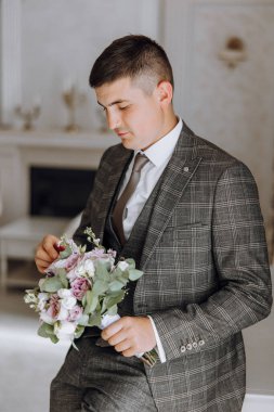Elinde bir buket çiçek tutan takım elbiseli ve kravatlı bir adam. Zarafet ve entelektüellik kavramı. Çünkü adam resmi giyinmiş ve elinde güzel bir buket tutuyor.