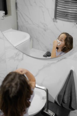 Genç bir kız aynanın önünde burnundan sümük salıyor.