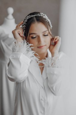 Beyaz bir elbise ve saç bandı takan bir kadın. Gülümsüyor ve kameraya bakıyor.