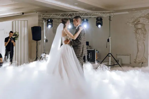 Bir gelin ve damat etraflarını saran bir duman bulutuyla havada dans ediyorlar. Sahne romantik ve rüya gibi.