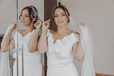 Bir kadın düğününe hazırlanıyor, duvağını takıyor ve saçını düzeltiyor. Büyük gün için heyecan ve beklenti kavramı