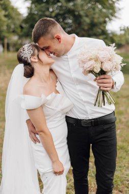 Gelin ve damat bir tarlada duruyorlar, gelin bir buket çiçek tutuyor. Sahne mutlu ve romantik, çünkü çift düğün günlerini kutluyor.