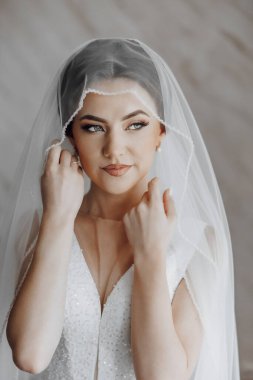 Bir kadın peçe takıyor ve gülümsüyor. Beyaz bir elbise giyiyor ve elleri başının üstünde.