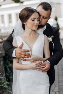 Bir gelin ve damat tuğla bir yolda birbirlerine sarılıyorlar. Gelin beyaz bir elbise giyiyor ve damat siyah bir takım elbise giyiyor. Sahne aşk ve mutluluktur.