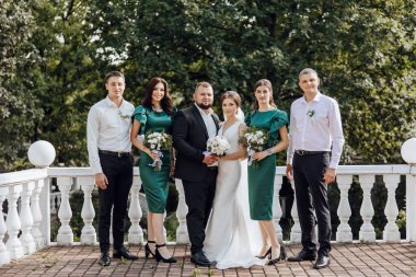 Gelin ve damat da dahil olmak üzere bir grup insan balkonda fotoğraf için poz veriyor.