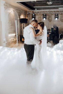 Gelin ve damat sisli bir arka planda havada dans ediyorlar. Sahne romantik ve rüya gibi.