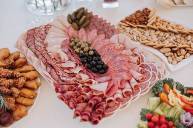 Etler, sebzeler ve krakerler dahil çeşitli yiyeceklerin olduğu bir masa. Masa parti ya da toplanma için hazırlandı.