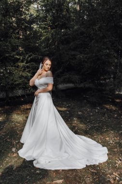 Beyaz elbiseli bir kadın ormanda duruyor.