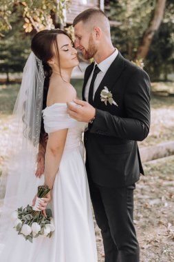 Gelin ve damat bir tarlada birlikte duruyorlar. Gelin ellerinde çiçeklerle.