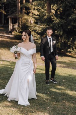 Gelin ve damat çimenli bir tarlada duruyorlar, gelin elinde bir buket çiçekle. Sahne büyük ihtimalle bir düğün merasimi, çünkü çift resmi giyinmiş.