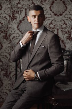 Takım elbiseli bir adam masada oturuyor ve kravatını düzeltiyor. Formalite ve profesyonellik kavramı. Çünkü adam takım elbise ve kravat giymiş.