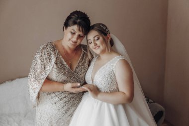 Gelinlikli bir kadın başka bir kadına sarılıyor.